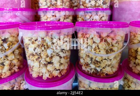 Delicious unbranded sweet and salty popcorn in plastic containers with pink lids Stock Photo