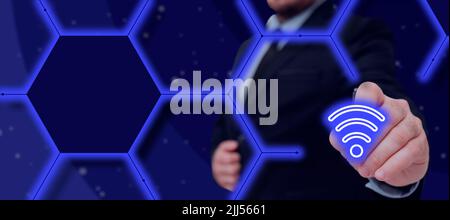 Businessman With A Pen Pointing On A Glowing Wi-Fi Signal In A Glowing Hexagon Design. Man In A Suit Presenting Digital Connection And Wireless Stock Photo