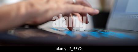 Wide view image of female fingers typing on glowing portable laptop computer keyboard. Low angle closeup shot. Stock Photo