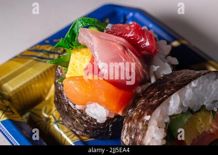 Takeout Kaisen Maki Zushi in plastic food tray. Norimaki in image rolled out by Shiso leaf, salmon, fried egg(Tamago Yaki), tuna (Maguro) and cucumber Stock Photo