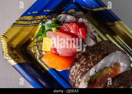 Takeout Kaisen Maki Zushi in plastic food tray. Norimaki in image rolled out by Shiso leaf, salmon, fried egg(Tamago Yaki), tuna (Maguro) and cucumber Stock Photo