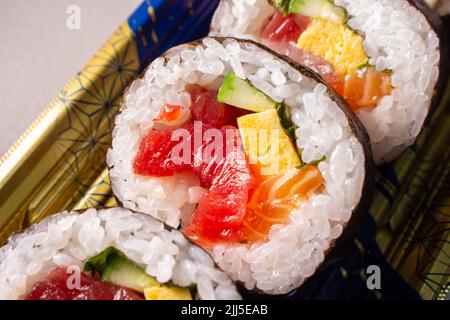 Takeout Kaisen Maki Zushi in plastic food tray. Norimaki in image rolled out by Shiso leaf, salmon, fried egg(Tamago Yaki), tuna (Maguro) and cucumber Stock Photo