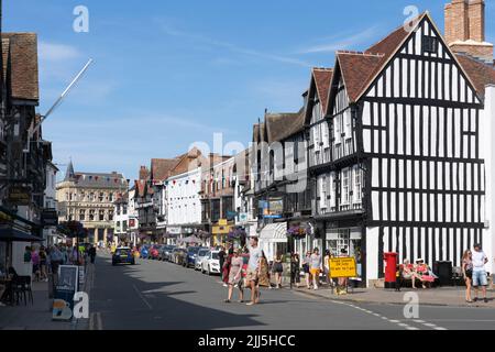 Shoppers and visitors to Stratford upon Avon on the High Street in July, with historic timber framed and plaster infill walled buildings. England Stock Photo