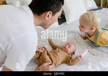 Man and boy playing with baby on bed at home Stock Photo
