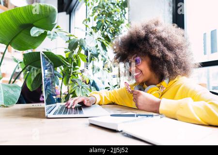 Happy girl using laptop with candy sitting in cafe Stock Photo