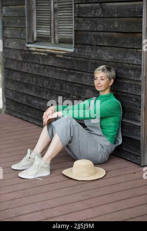 Thoughtful woman sitting on porch Stock Photo