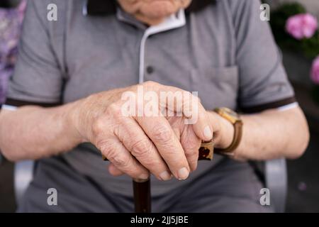 Hands of senior man holding walking cane Stock Photo