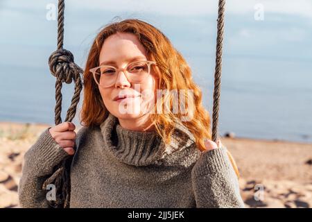 Young woman on swing at beach Stock Photo