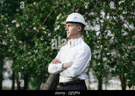 Architect with arms crossed standing in front of apple tree Stock Photo