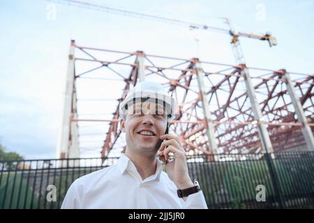 Happy engineer talking on smart phone at construction industry Stock Photo