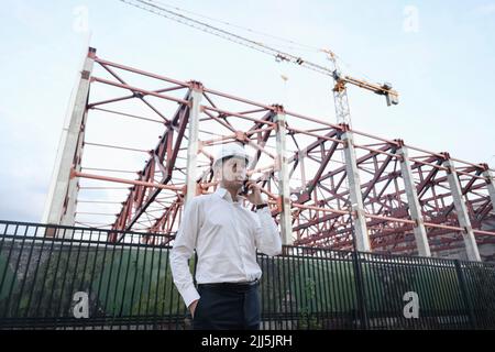 Engineer talking on smart phone standing at construction site Stock Photo