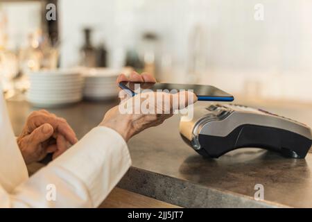 Senior woman making payment through mobile phone Stock Photo