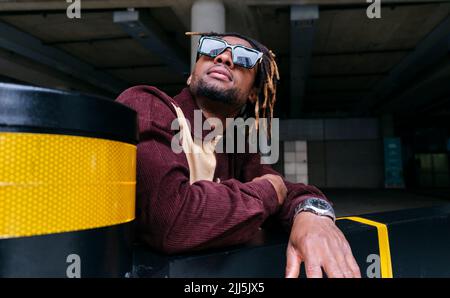 Man looking up wearing sunglasses by wall Stock Photo