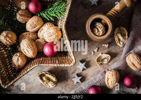 Studio shot of cutting board, star shaped wicker basket, Christmas ornaments, walnuts and simple nutcracker Stock Photo