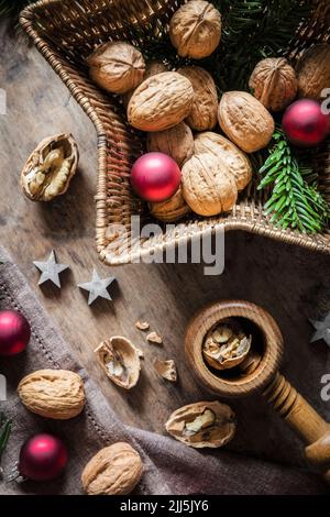 Studio shot of cutting board, star shaped wicker basket, Christmas ornaments, walnuts and simple nutcracker Stock Photo