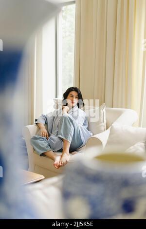 Woman sitting on sofa at home Stock Photo