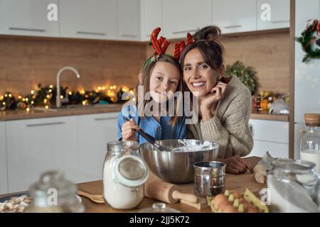 Smiling woman and daughter with mixing bowl in kitchen Stock Photo