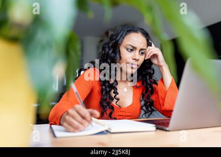 Freelancer with head in hand using laptop at home office Stock Photo