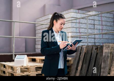Businesswoman working on tablet PC at factory Stock Photo