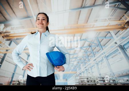 Smiling female architect with hardhat in industry Stock Photo