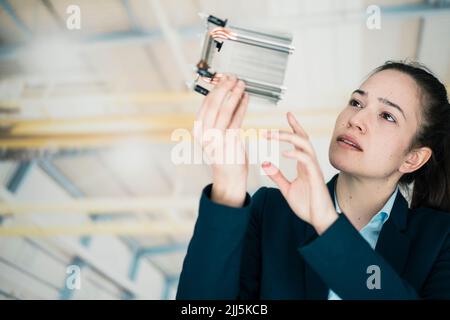 Businesswoman analyzing machine part in factory Stock Photo