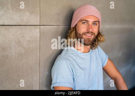 Smiling man wearing knit hat by wall Stock Photo