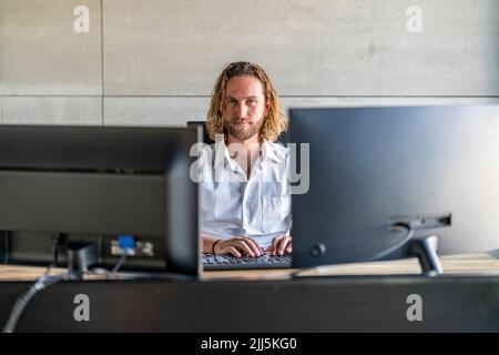 Confident executive with computers at desk in office Stock Photo