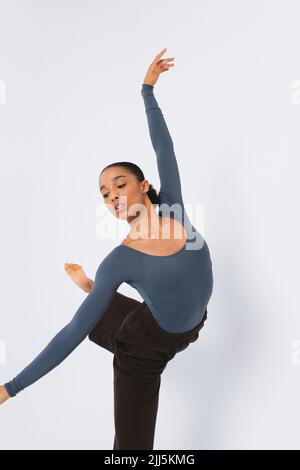 Young ballet dancer with arm raised against white background Stock Photo