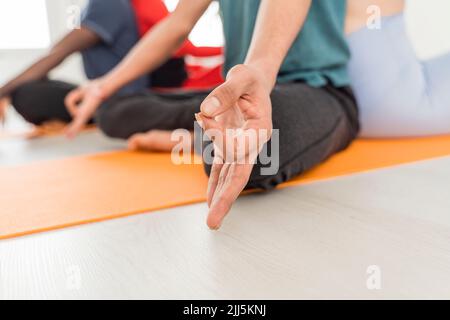 Hand of man meditating with friends at yoga studio Stock Photo