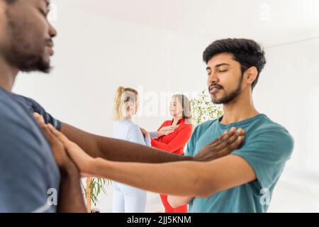 Friends with eyes closed touching chest practicing yoga at studio Stock Photo