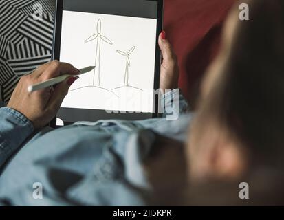 Freelancer making sketch of wind turbines on graphics tablet at home Stock Photo