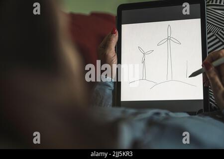 Freelancer making sketch of wind turbines on graphics tablet at home office Stock Photo