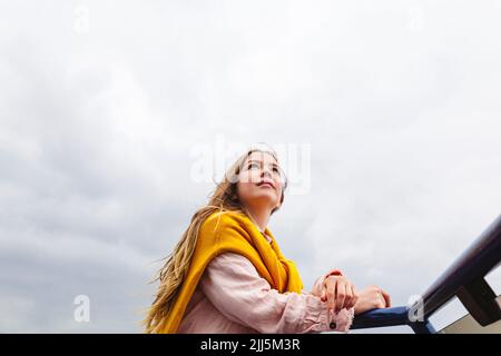 Young woman standing under cloudy sky Stock Photo