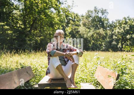 Senior man sitting on picnic table in park Stock Photo