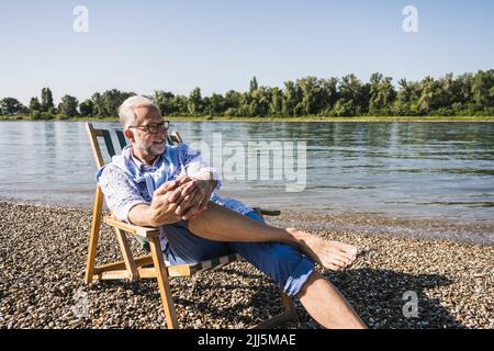 Smiling senior man wearing eyeglasses at riverbank Stock Photo