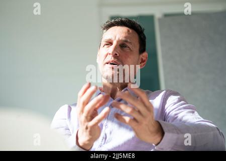 Businessman gesturing in front of wall at office Stock Photo