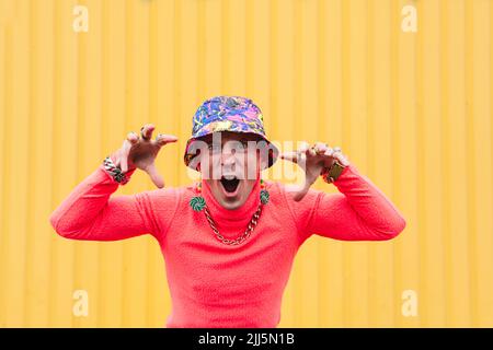 Mature man with mouth open gesturing in front of yellow wall Stock Photo