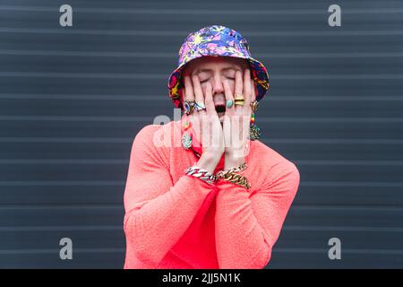 Mature man wearing hat covering face with hands in front of wall Stock Photo