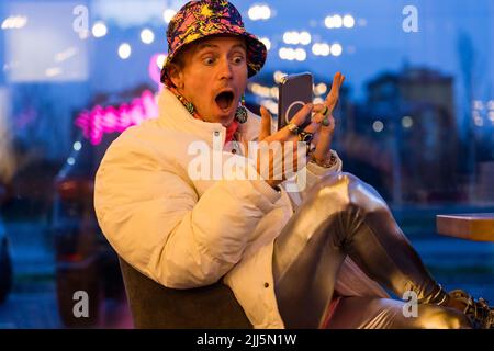 Surprised man using smart phone sitting in bar Stock Photo