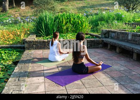 Girl sitting with yoga coach meditating in park Stock Photo