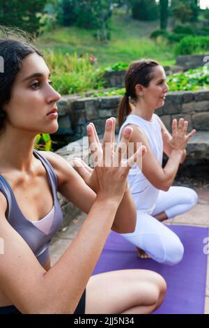 Teenage girl with hands clasped exercising with instructor at park Stock Photo