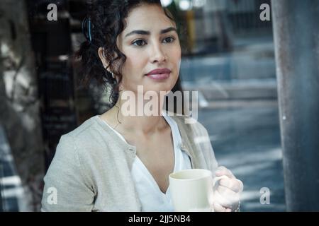Thoughtful woman holding coffee cup seen through glass window Stock Photo