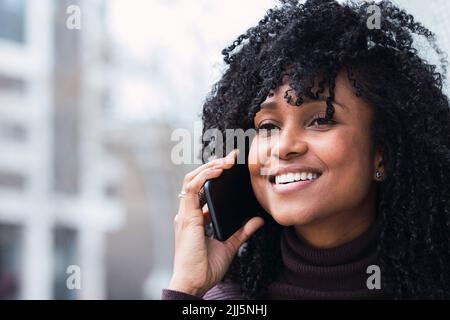 Happy woman with curly hair talking on smart phone Stock Photo