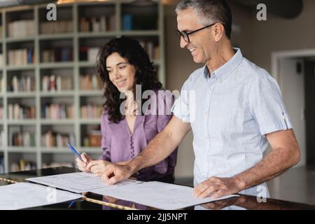 Smiling colleagues looking at business plan on table at office Stock Photo