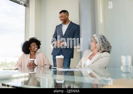 Businessman leaning on column discussing with colleagues at office Stock Photo