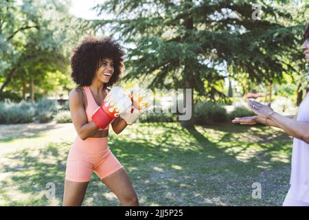 Happy Afro woman boxing by mother in park Stock Photo