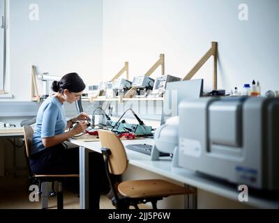 Engineer sitting on chair working in electronics laboratory Stock Photo