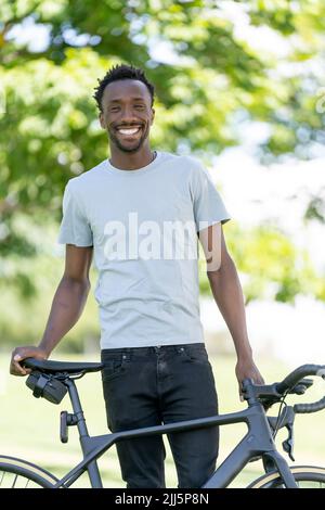 Happy young man with bicycle in park Stock Photo