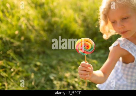 Girl holding rainbow lollipop on sunny day Stock Photo