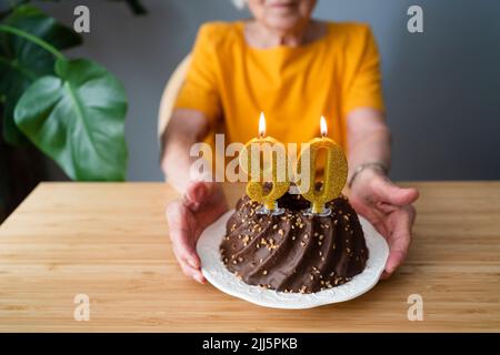 Senior woman with birthday cake sitting at table Stock Photo